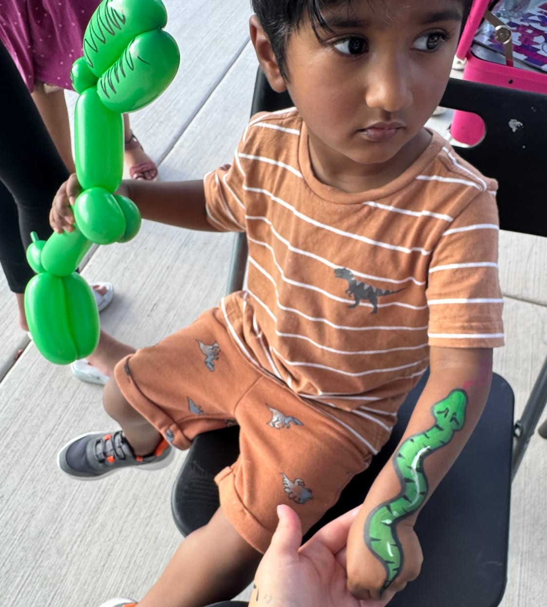 Dinosaur balloon and snake face painting at a Texas kids party