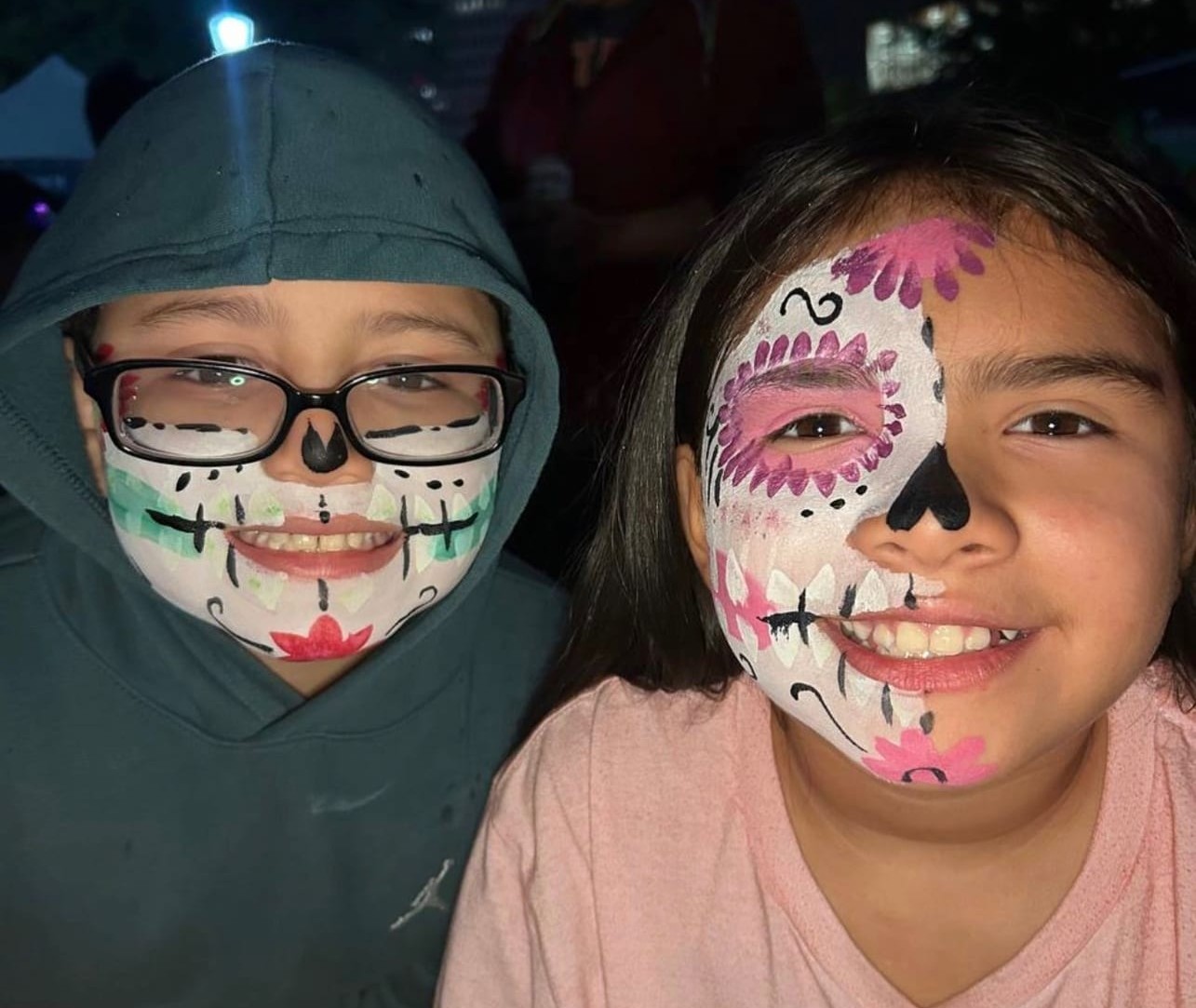 Matching sugar skull face painting for siblings at a Texas party