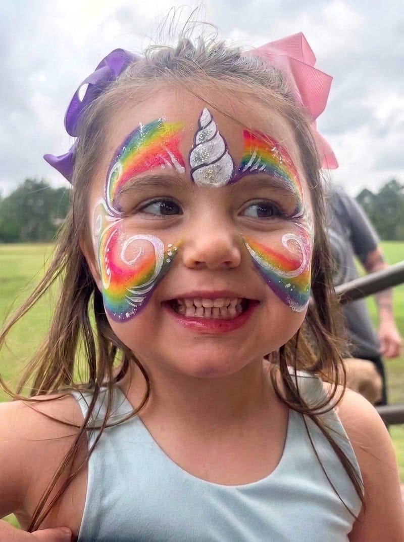 Girl with a rainbow unicorn face painting at a Texas birthday party